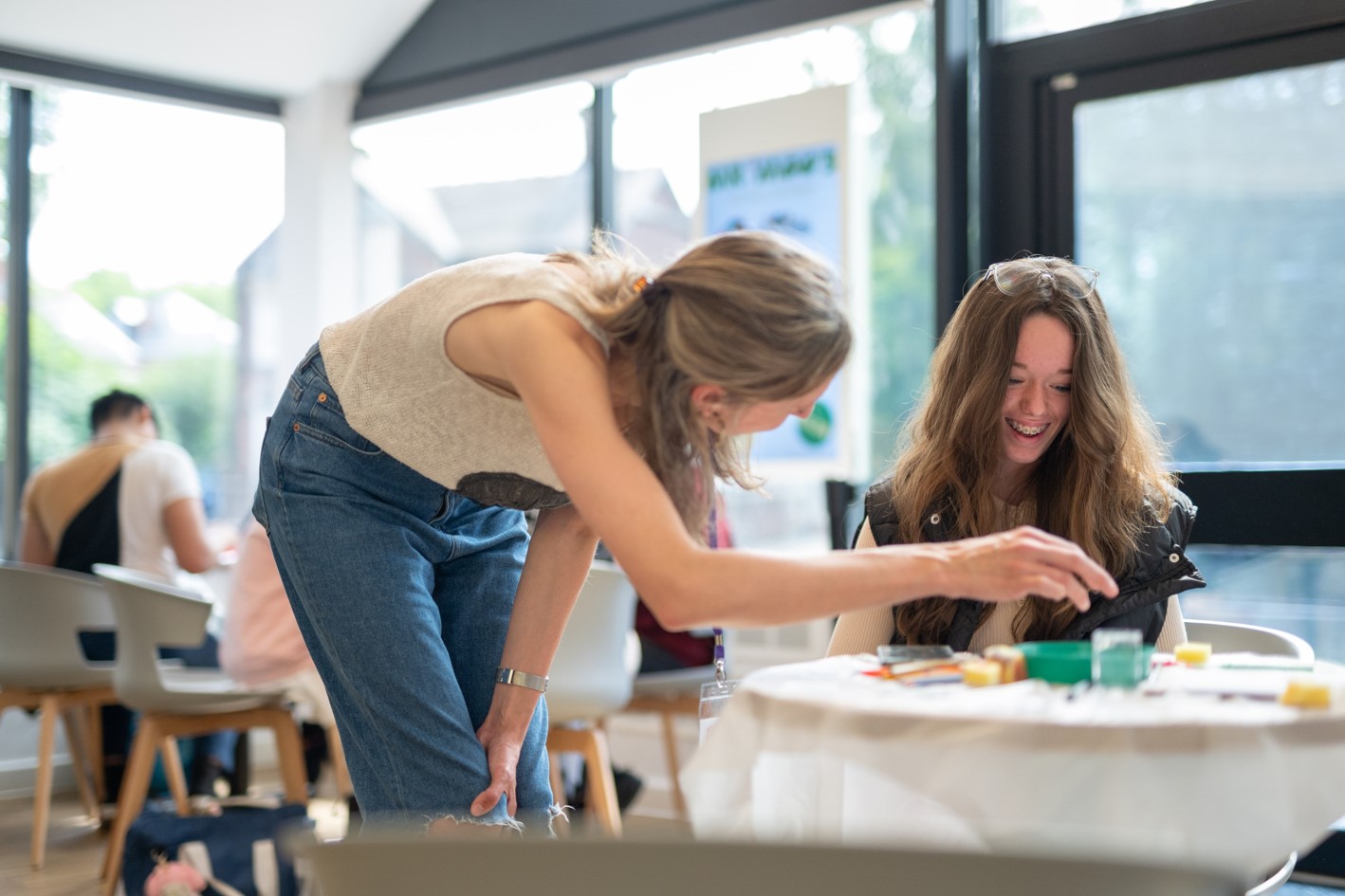 A young person smiles for the camera as someone comments on their work.