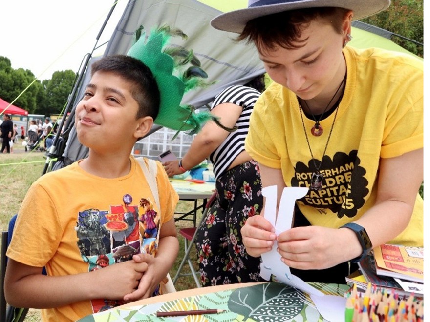 A trainee helps a child take part in a craft activity.