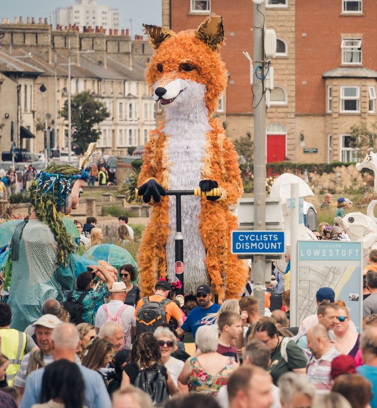 A giant fox puppet is paraded through a town centre