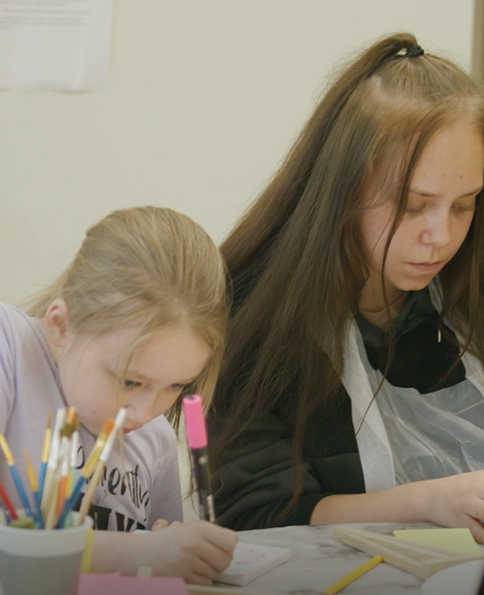 2 young women focus on painting and drawing a piece of artwork